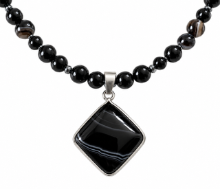 Close up of Smoke Stone black agate pendant featuring natural banded details and metallic setting.